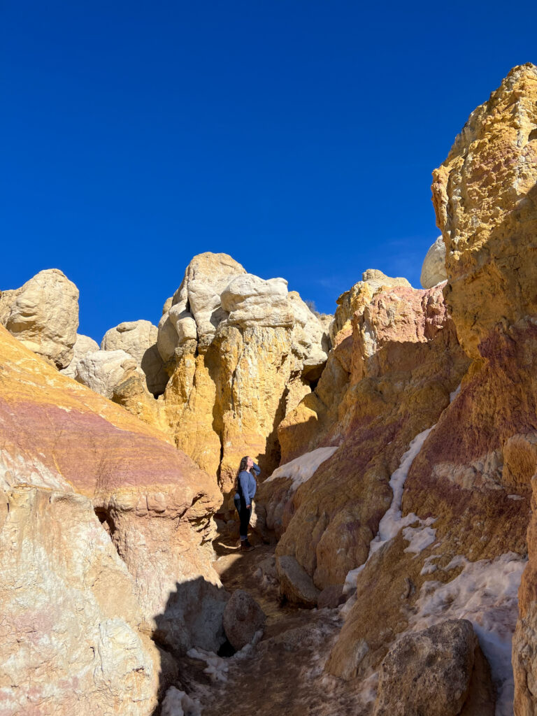 girl looks up at colorful rocks at interpretive paint mines