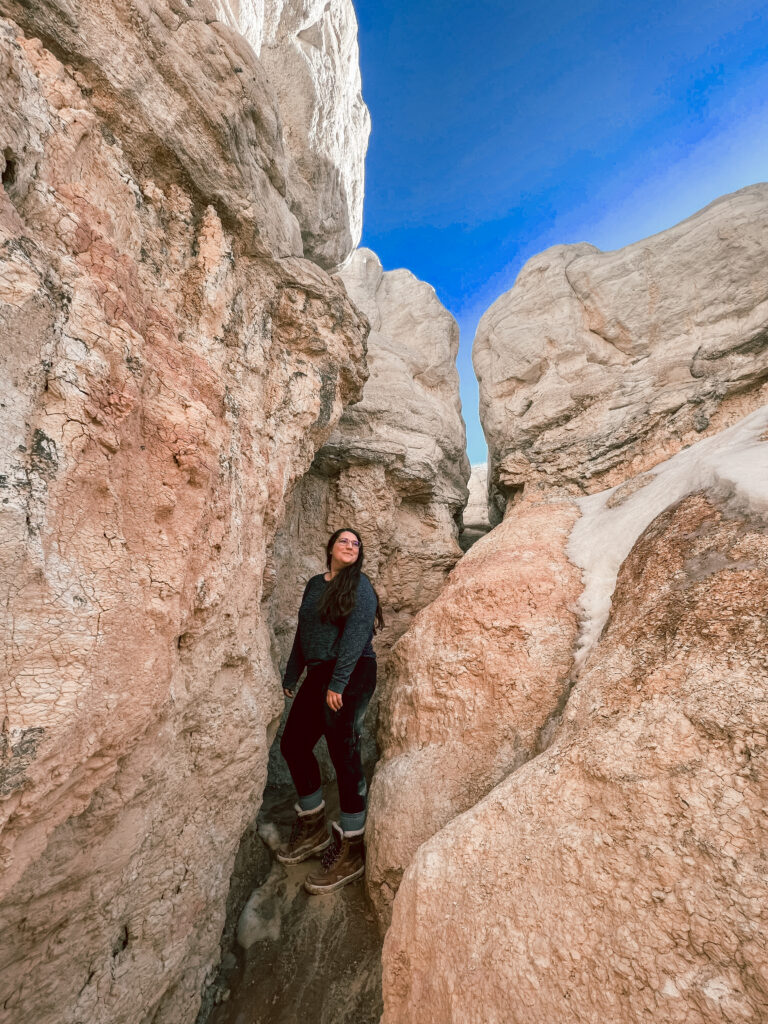 girl stands between colorful rock formations at interpretive paint mines park