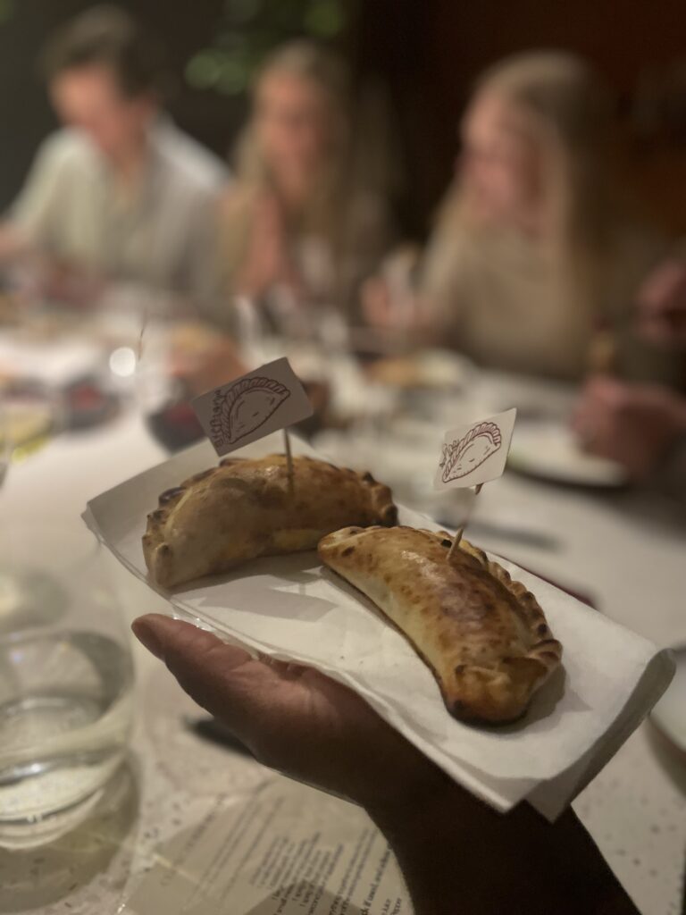 girl holds out two homemade empanadas on a napkin at a fancy dinner event