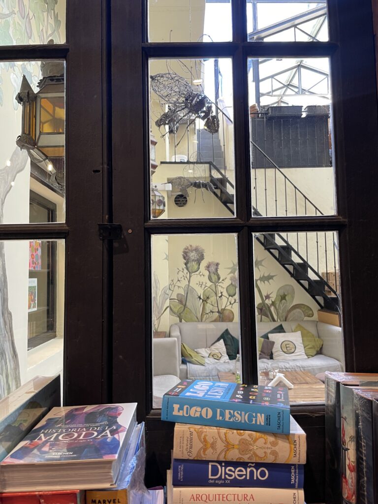 books are stacked next to a window overlooking a courtyard