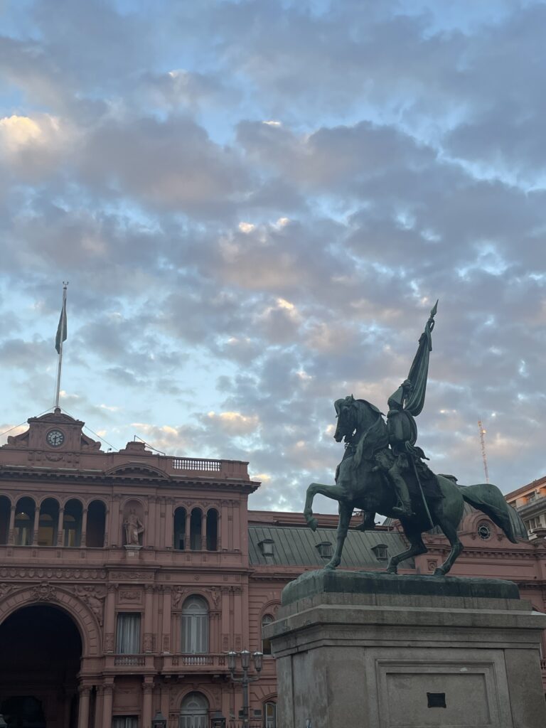 sunset view of casa rosada (the president's house) with a statue in front